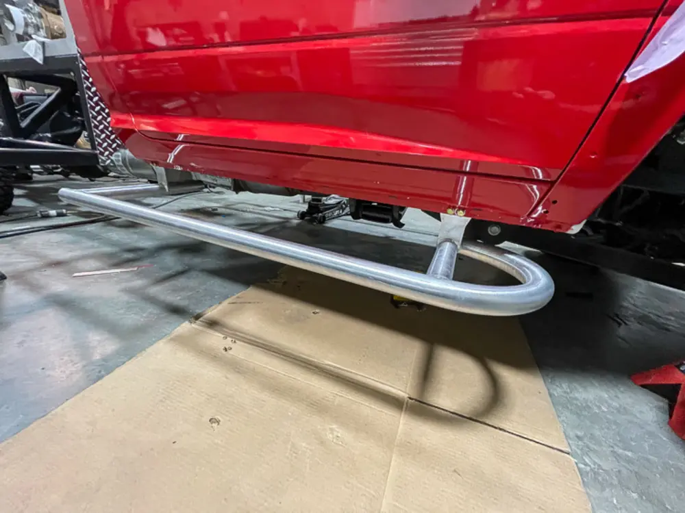 Exterior view of small fire truck showing cab, body compartments, and wheel/tire area.